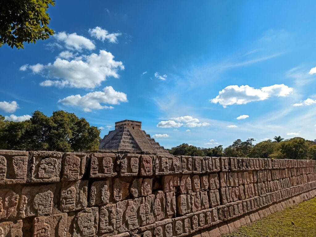 Chichen Itza Tours a stone wall with a pyramid in the background