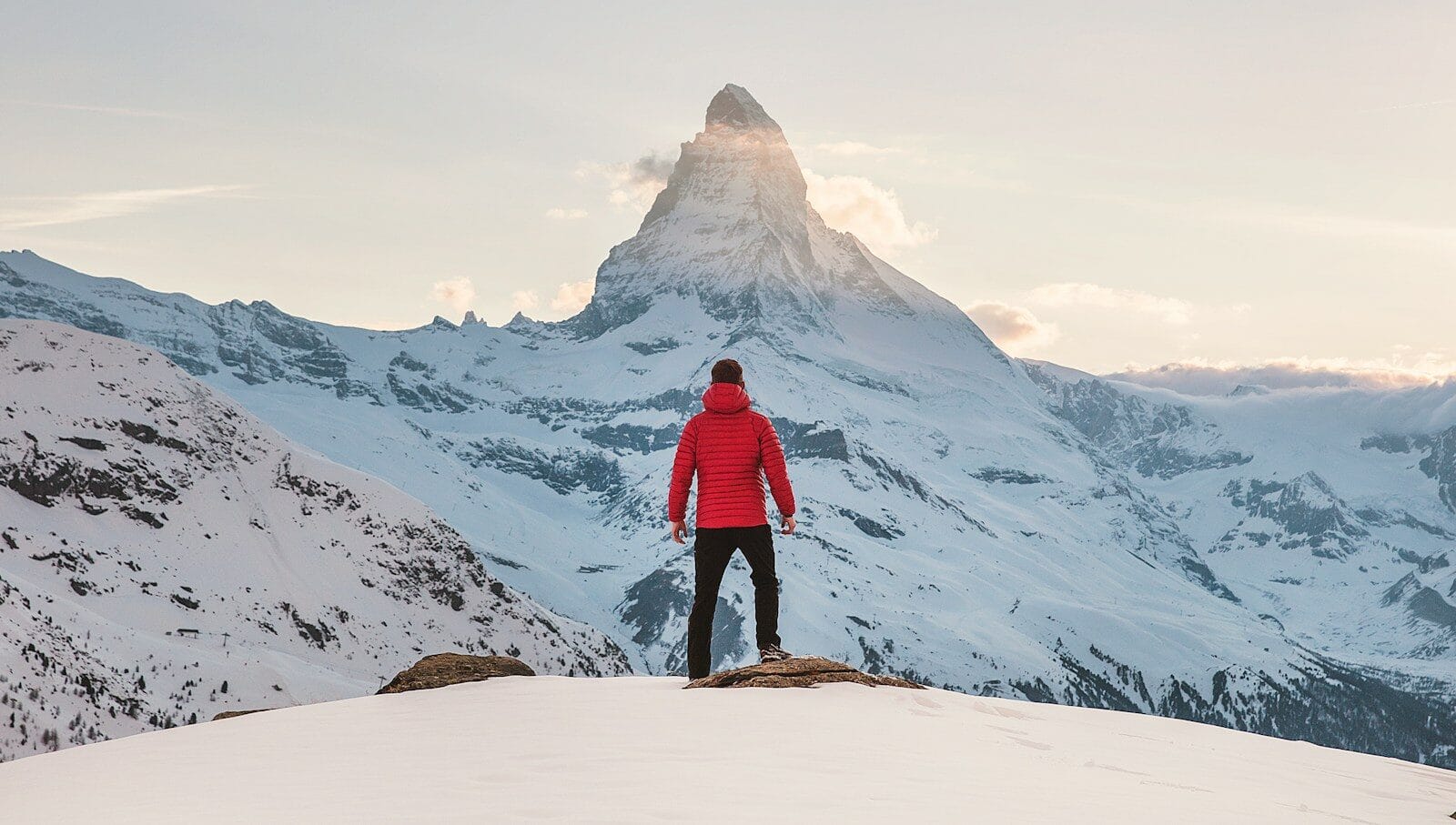 about us trendiscovers person in red hoodie standing on snowy mountain during daytime