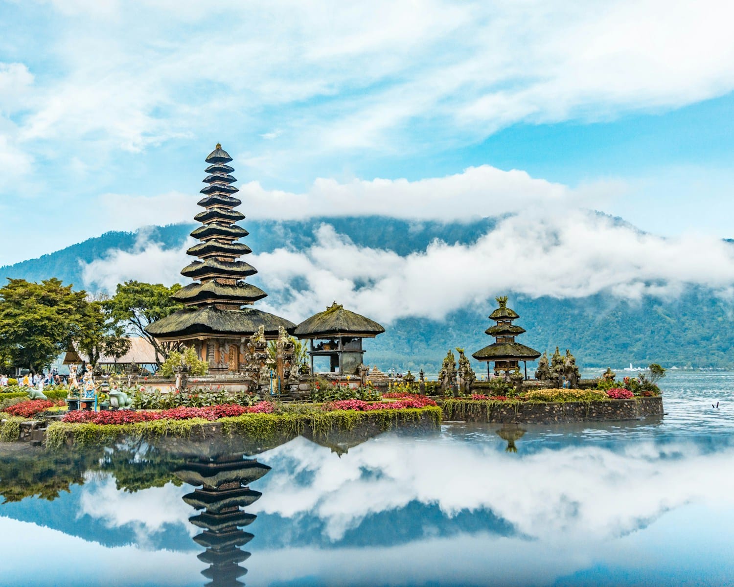 Bali Tours brown and green temple near body of water under blue and white cloudy sky during daytime