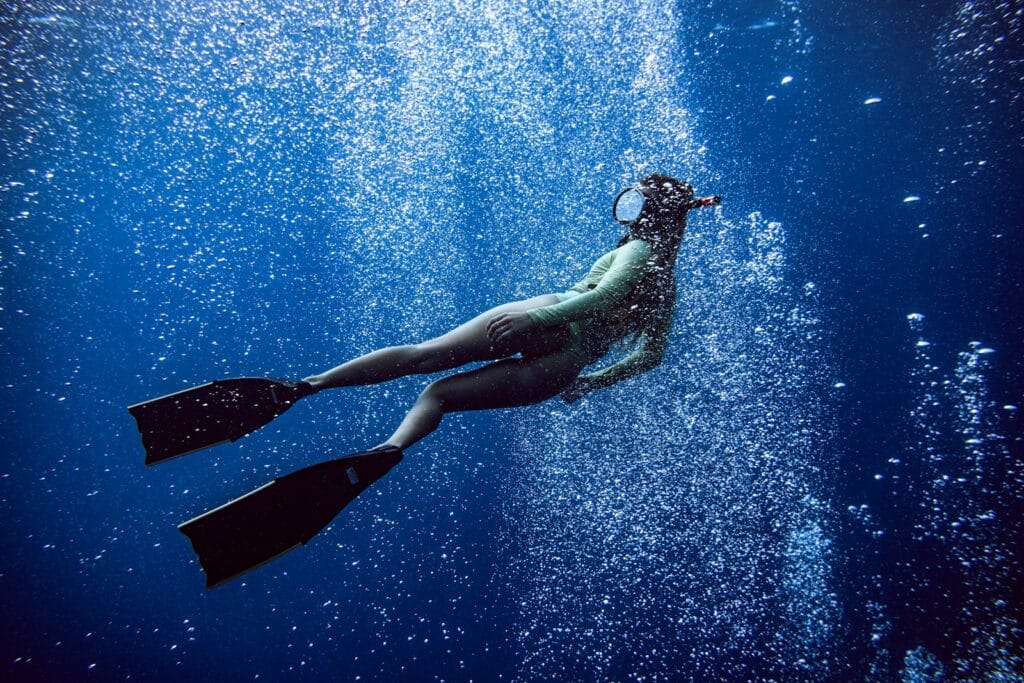 Bonaire Tours woman in black one piece swimsuit under water