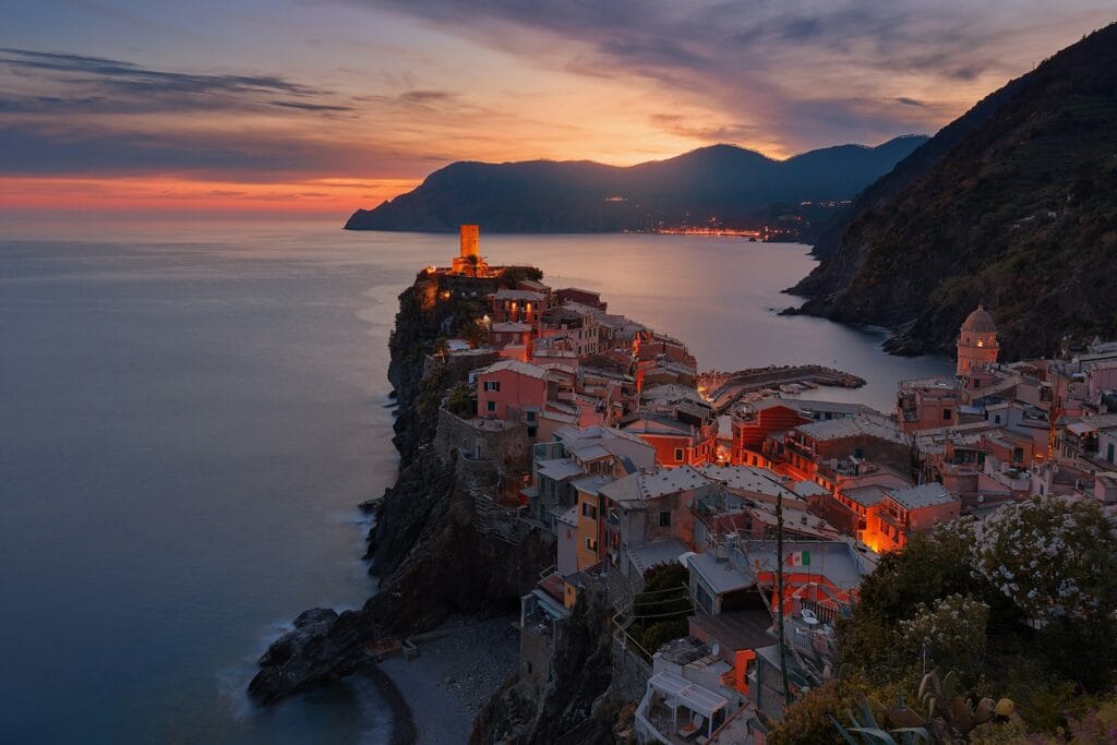 Europe Travel Guide aerial view of village on mountain cliff during orange sunset