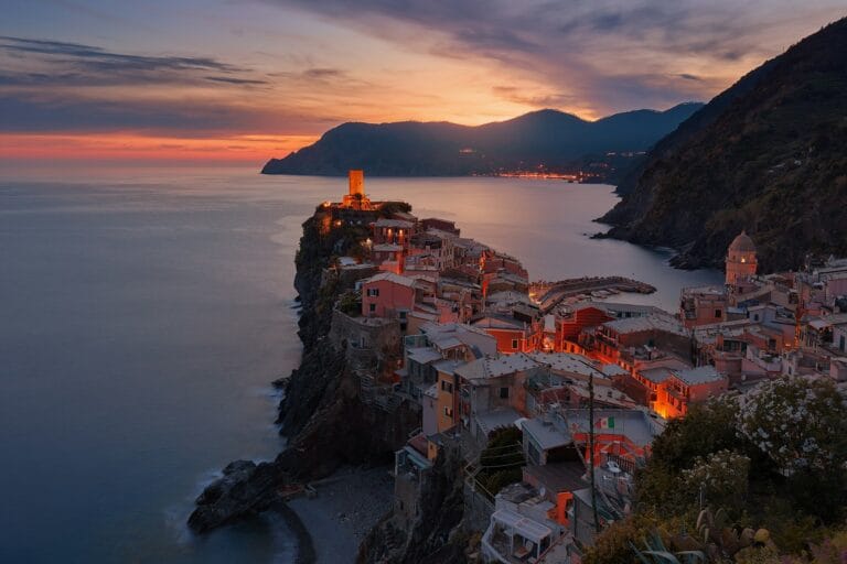 Europe Travel Guide aerial view of village on mountain cliff during orange sunset