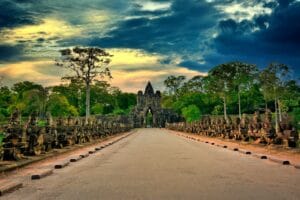 Cambodia Tours gray concrete road between green trees under blue sky and white clouds during daytime
