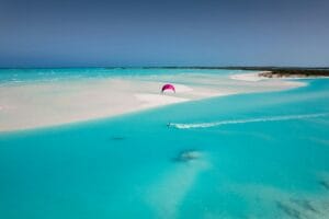 Bahamas Travel Guide a pink umbrella is in the middle of a blue lagoon