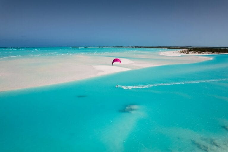 Bahamas Travel Guide a pink umbrella is in the middle of a blue lagoon
