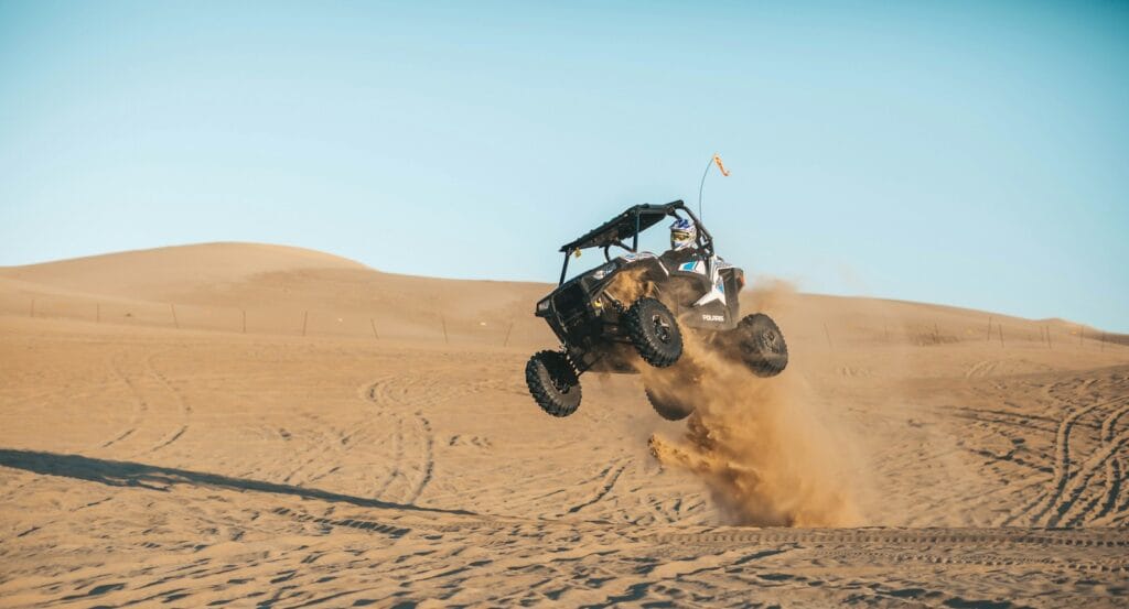 adrenaline man riding on UTV on desert during daytime