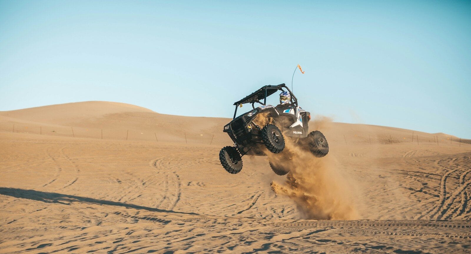 adrenaline man riding on UTV on desert during daytime