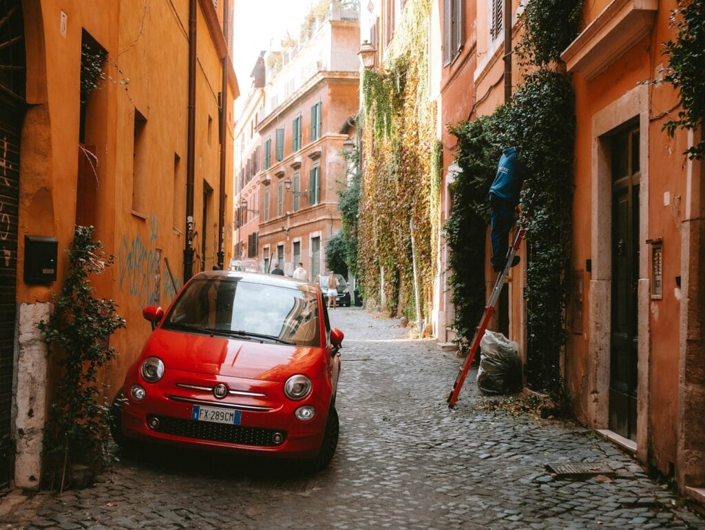 Sistine Chapel Trastevere A red car is parked on a narrow street
