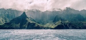 Kauai Travel Guide body of water near mountain under cloudy sky during daytime