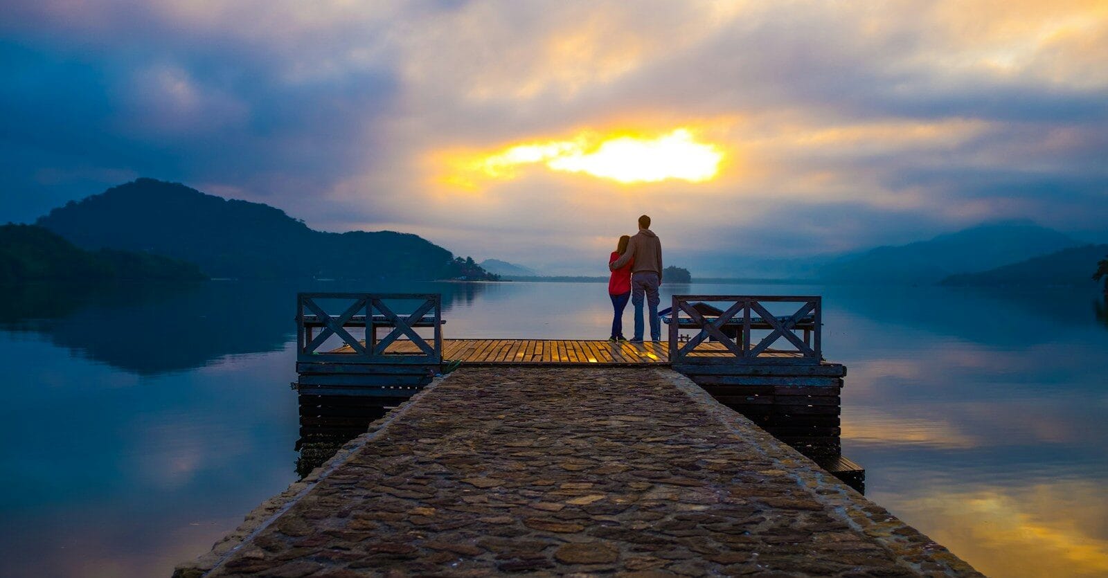 affiliate disclaimer couple standing on dock looking at sunset