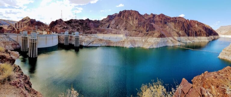 Hoover Dam Tours brown wooden dock on river near brown mountain under blue sky during daytime