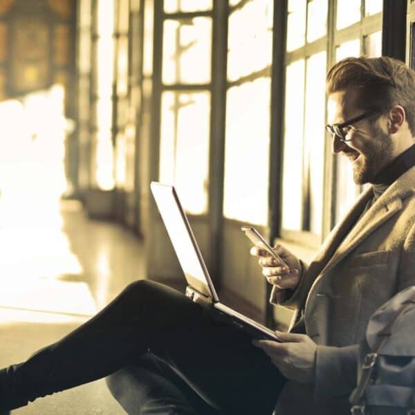 Airalo man sitting near window holding phone and laptop