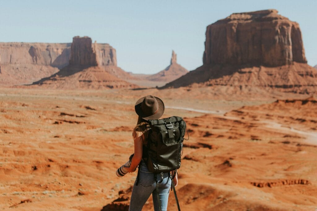 travel tips woman with black backpack standing on brown dessert