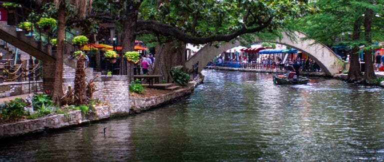 san antonio travel guide a canal with a bridge over it and people walking on it