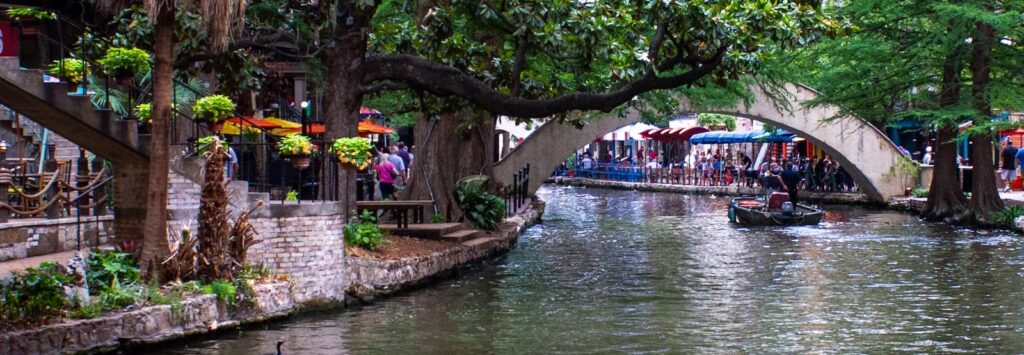 san antonio travel guide a canal with a bridge over it and people walking on it