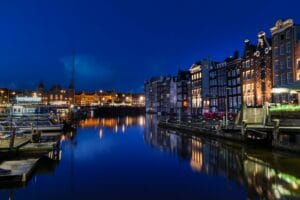 amsterdam travel guide buildings beside body of water during nighttime