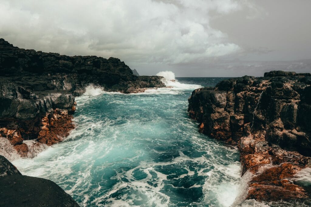 kauai tours ocean waves crashing on rocky shore during daytime