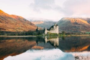 Scotland Tours gray concrete building near lake under white sky during daytime