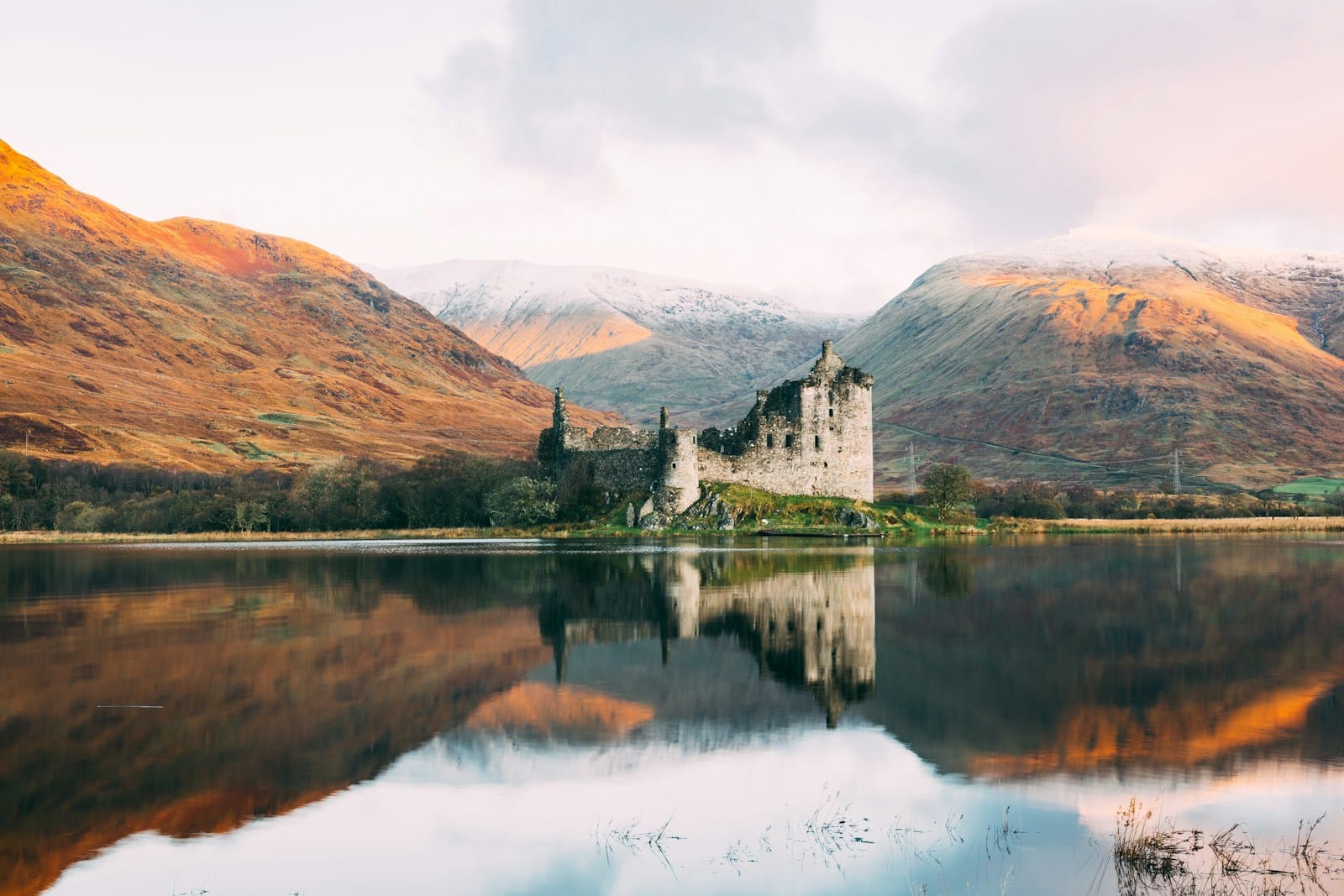 Scotland Tours gray concrete building near lake under white sky during daytime
