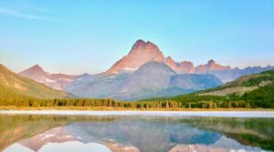 montana travel guide lake near green grass field and mountain under blue sky during daytime