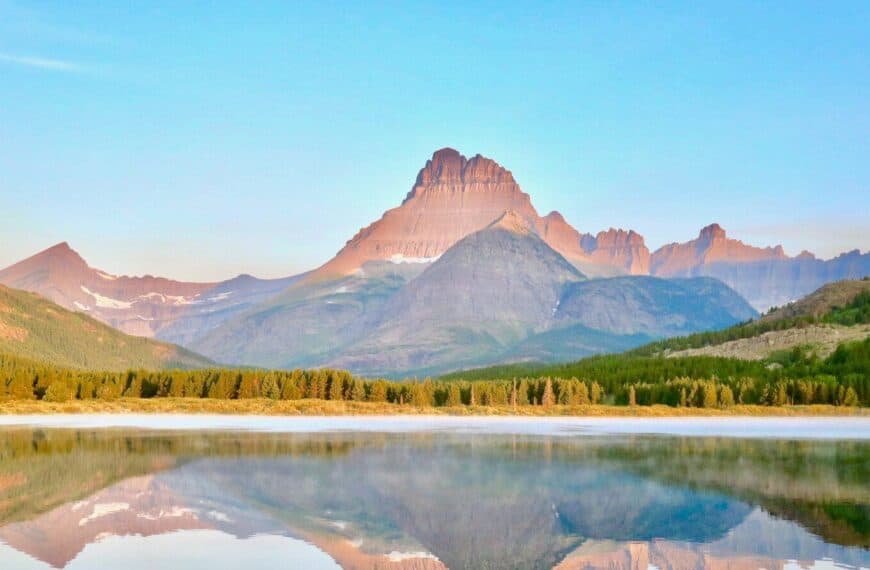 montana travel guide lake near green grass field and mountain under blue sky during daytime
