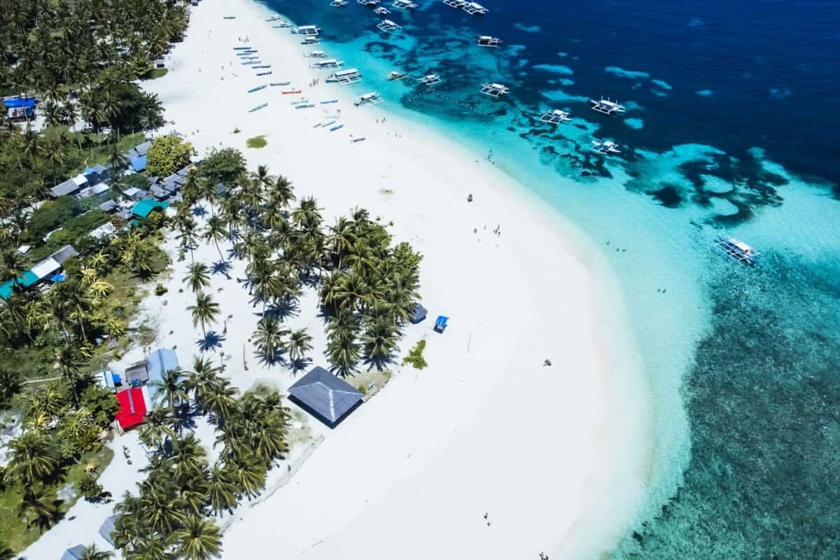 Siargao Island tours An aerial view of a tropical island with a white sand beach