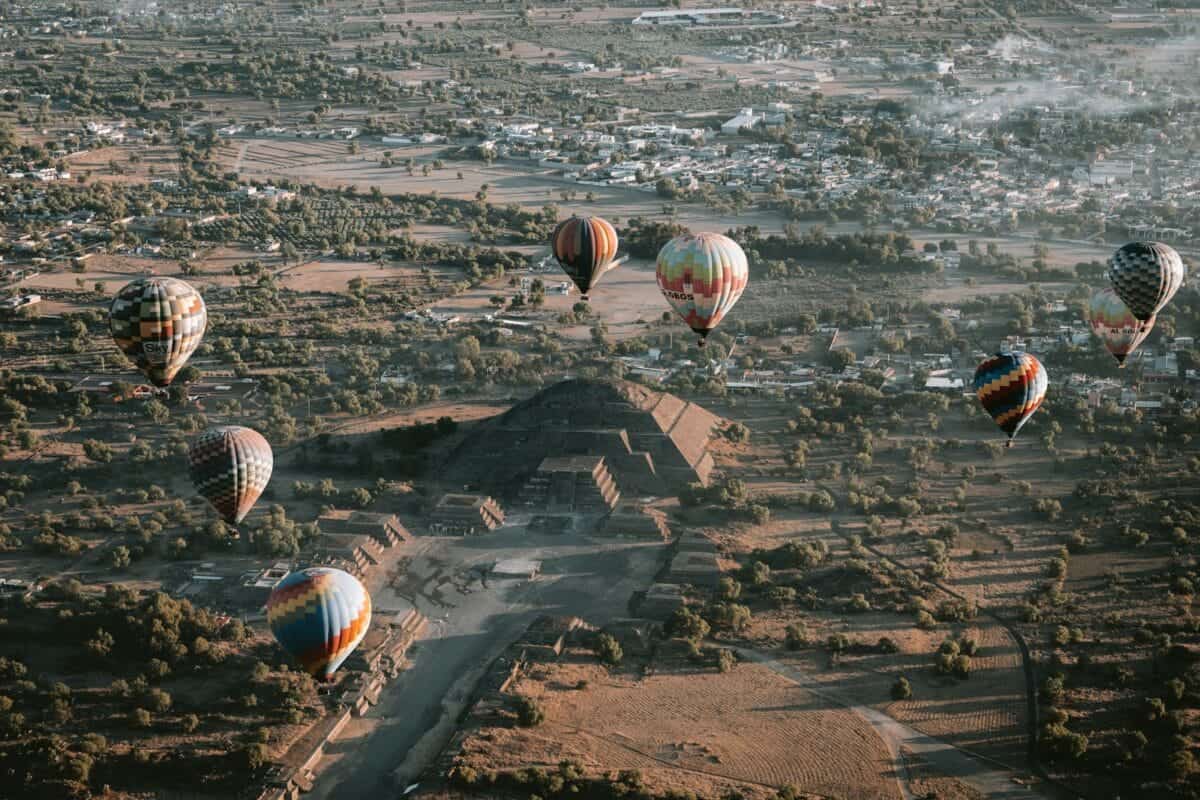 Teotihuacán Tours Hot air balloons soar over an ancient pyramid.