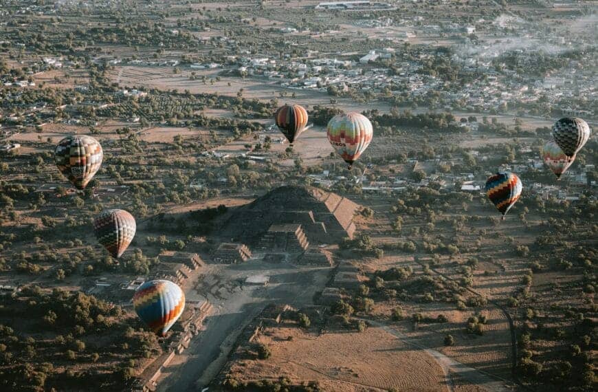 Teotihuacán Tours Hot air balloons soar over an ancient pyramid.