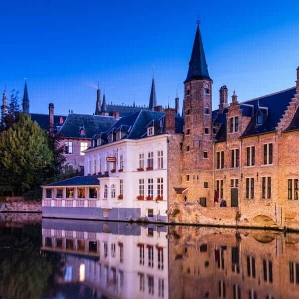 Bruges Travel Guide, brown and white concrete building near body of water during daytime