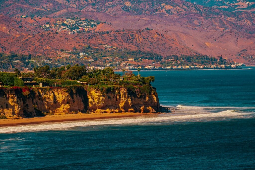 Malibu & Pacific Palisades a large body of water with a mountain in the background