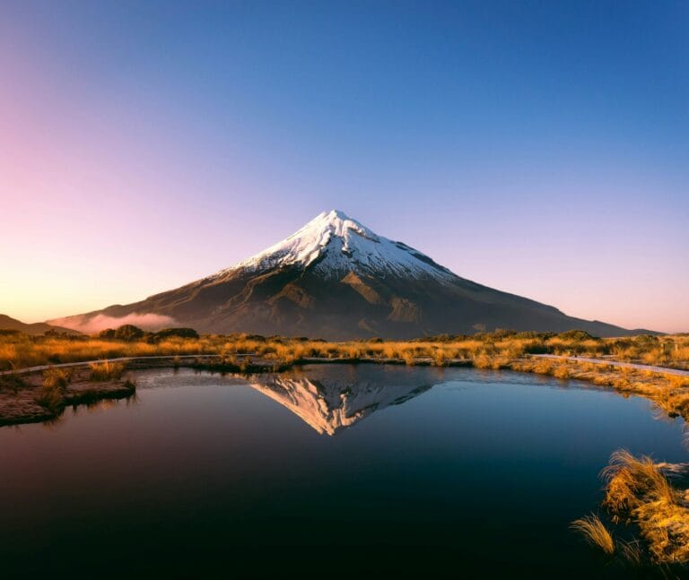 new zealand tours mountain near body of water during daytime