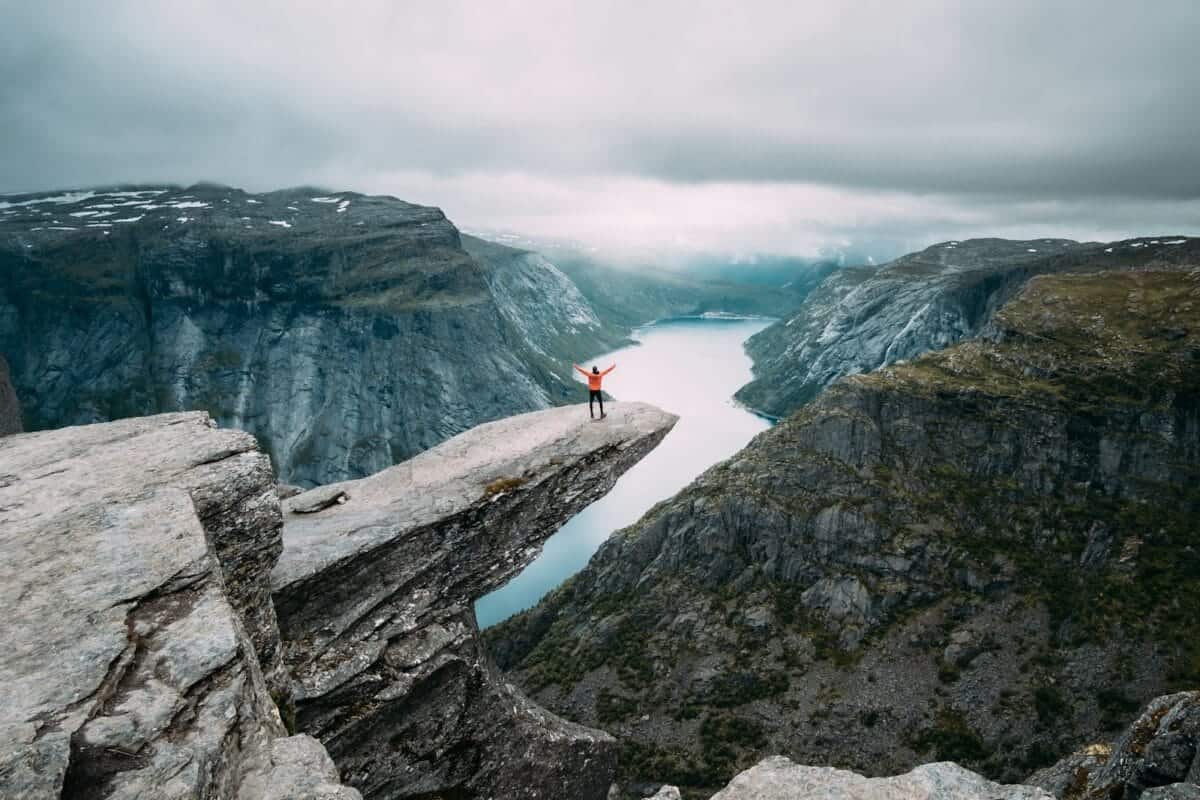 Norway Tours person standing on gray high-rise rock formation at daytime