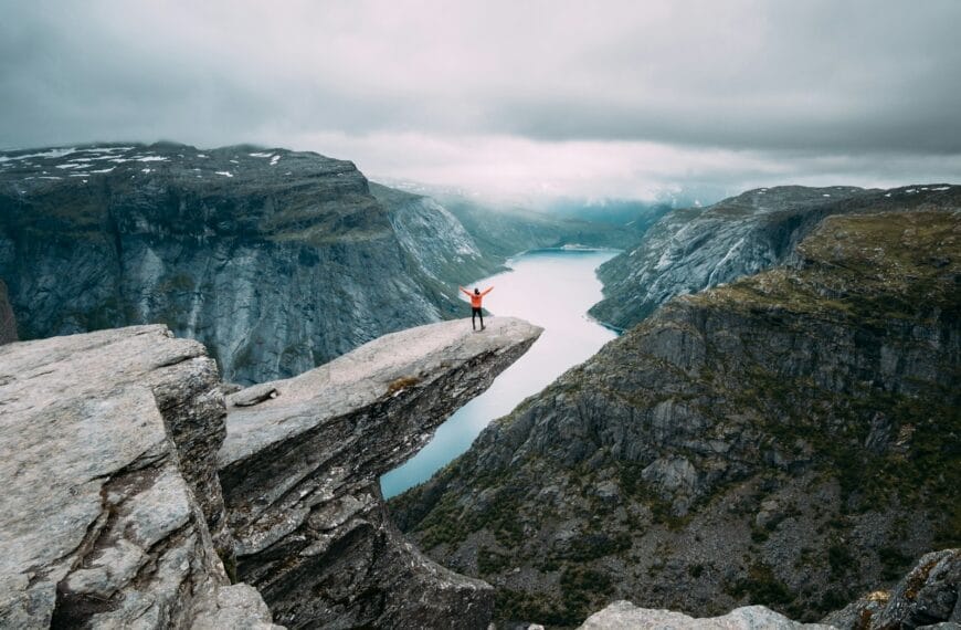 Norway Tours person standing on gray high-rise rock formation at daytime