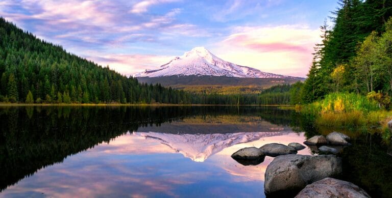 Oregon Travel Guide lake surrounded by pine trees near snow-covered mountain