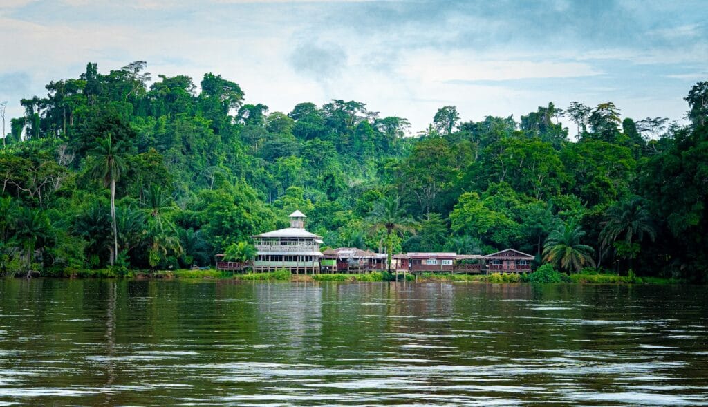 Central Africa Travel Guide Houses sit by a body of water in a forest.