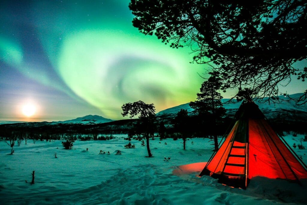 sweden tours orange tent on snow covered ground during night time
