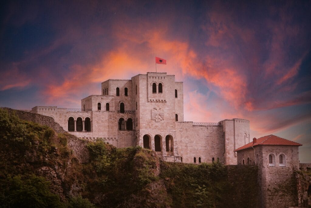 Albania Travel Guide A castle on a hill with a sunset in the background