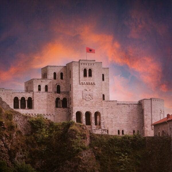 Albania Travel Guide A castle on a hill with a sunset in the background