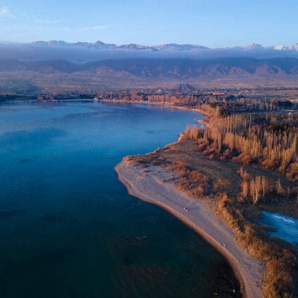Kyrgyzstan Travel Guide aerial view of body of water near trees during daytime