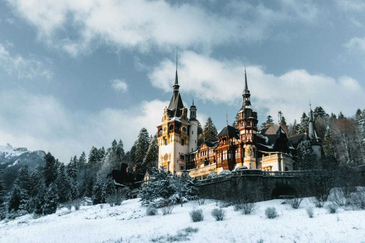 romania travel guide a castle in the snow with Peleș Castle in the background