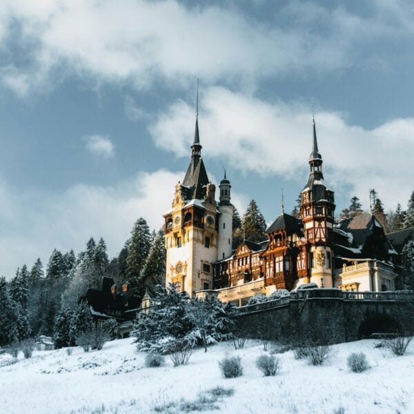 romania travel guide a castle in the snow with Peleș Castle in the background