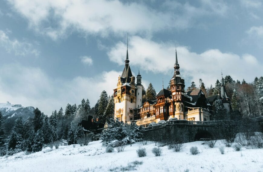 romania travel guide a castle in the snow with Peleș Castle in the background