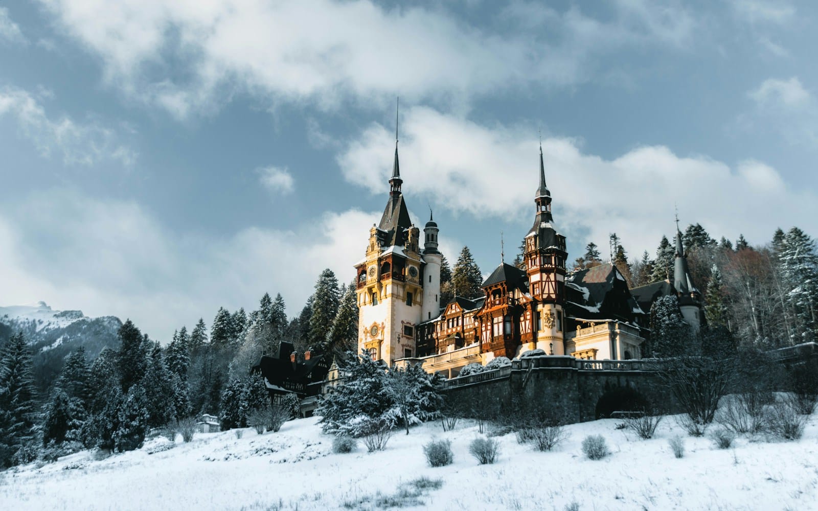 romania travel guide a castle in the snow with Peleș Castle in the background
