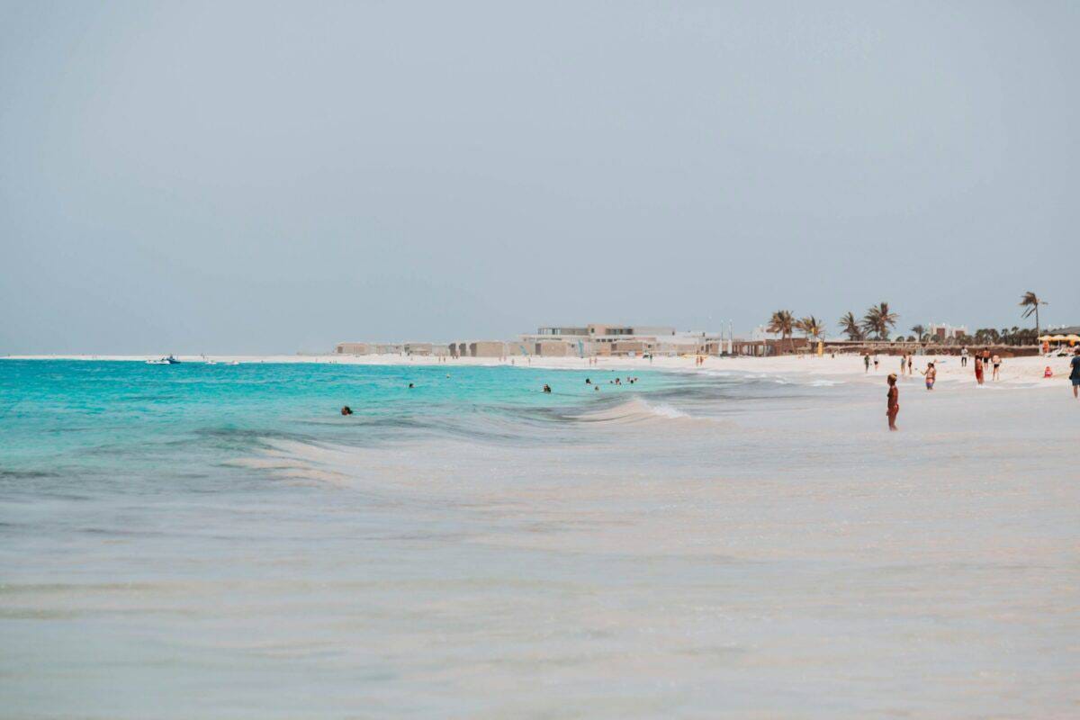 Cape Verde Travel Guide a group of people standing on top of a sandy beach
