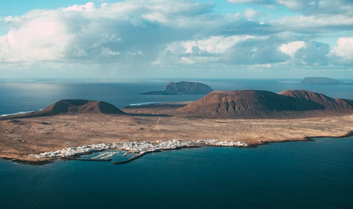 Canary Islands Travel Guide brown mountain near body of water under blue sky during daytime