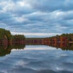 New England Travel Guide green trees beside river under cloudy sky during daytime
