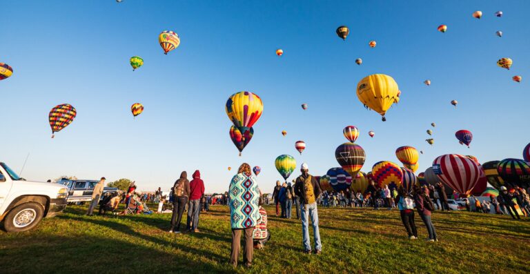 New Mexico Travel Guide hot air balloons on green grass field under blue sky during daytime