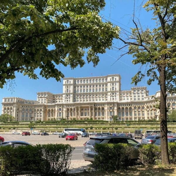 Bucharest Travel Guide a large building with a lot of cars parked in front of it