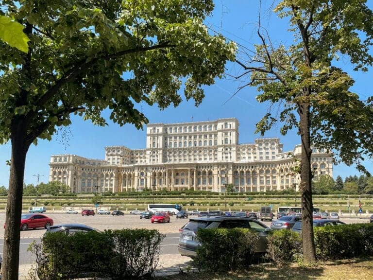 Bucharest Travel Guide a large building with a lot of cars parked in front of it