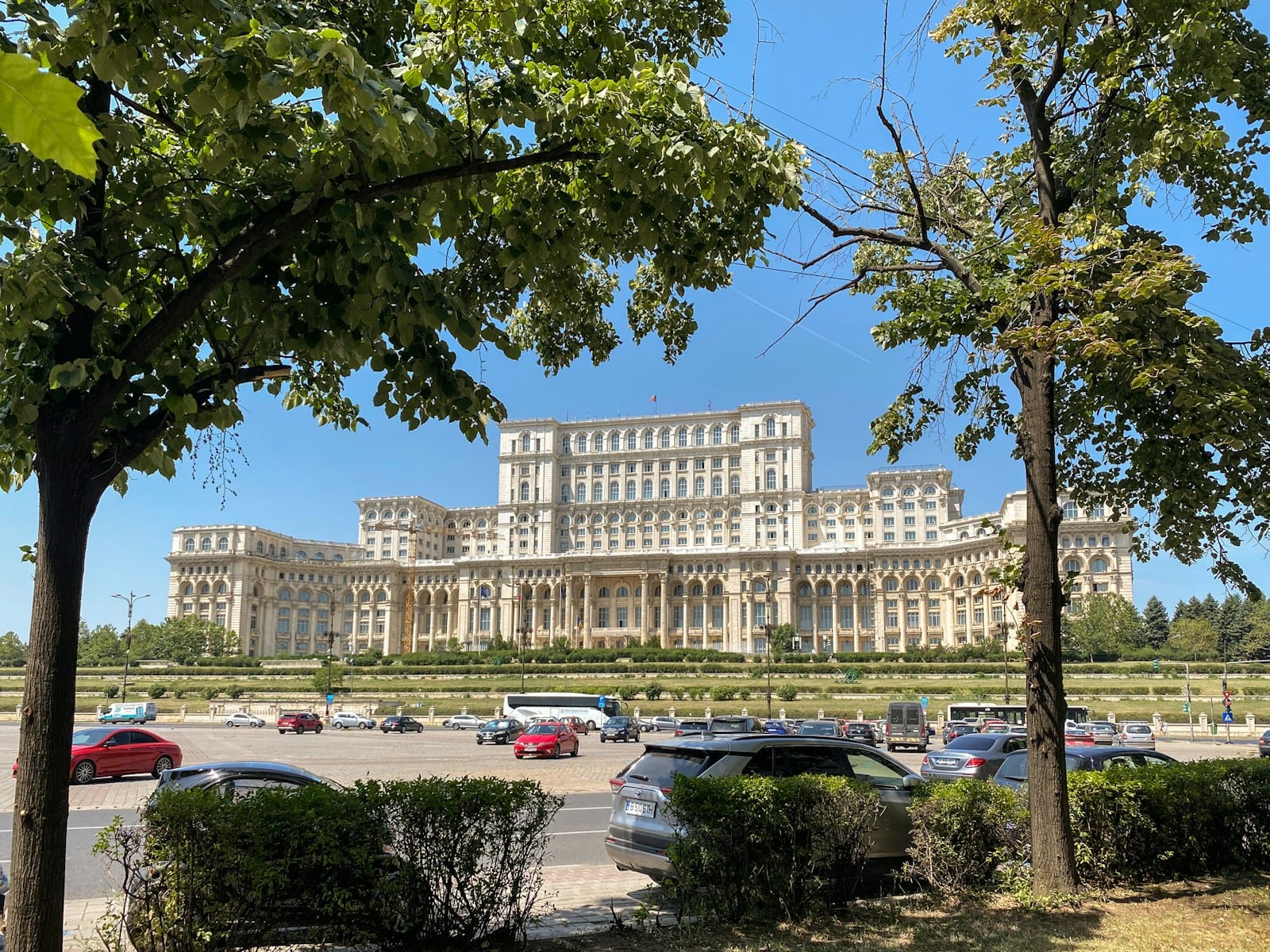 Bucharest Travel Guide a large building with a lot of cars parked in front of it